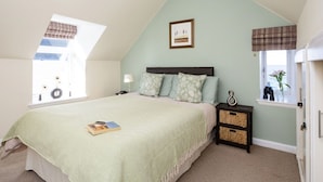A bedroom with a bed, a nightstand, a lamp, a window with a view, and a ceiling light. - Stunning  villa for 4 people with WIFI, TV and pets allowed (Fraserburgh)