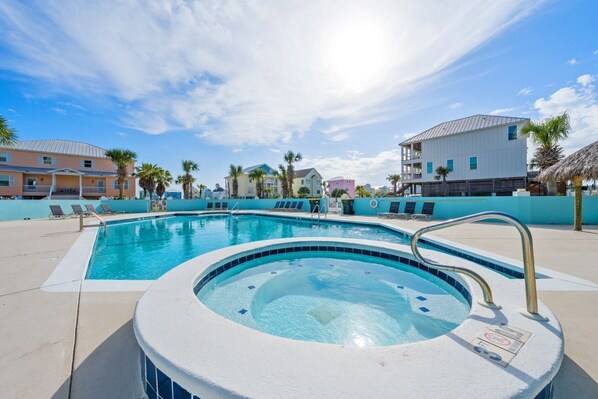 Une piscine avec des chaises longues, un jacuzzi et un ciel bleu azur.