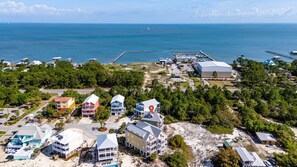 An aerial view of a coastal area with buildings, a dock, and a pier. - Spacious Family-Friendly | Pet-Friendly Beach House | Pool | Sleeps 10 (Gulf Shores)