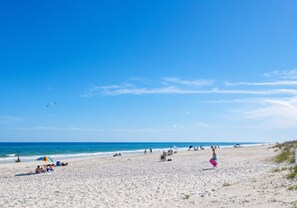 Une plage avec des gens, des parasols et un ciel dégagé.