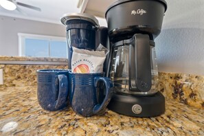 A coffee maker, two mugs, and a packet of coffee on a kitchen counter. - Spacious Family-Friendly | Pet-Friendly Beach House | Pool | Sleeps 10 (Gulf Shores)
