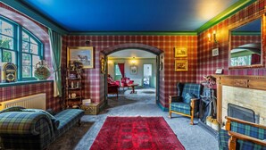 A cozy room with plaid wallpaper, a red carpet, and a fireplace.