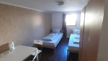 A compact room with a single bed, a small table, and a chair.