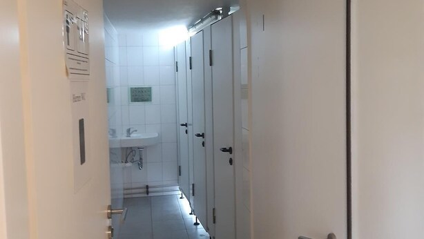 A corridor with a row of white lockers and a sink area at the end. - 2-Rent Group Hostel Rooms&Apartments EVE168 (Munich)