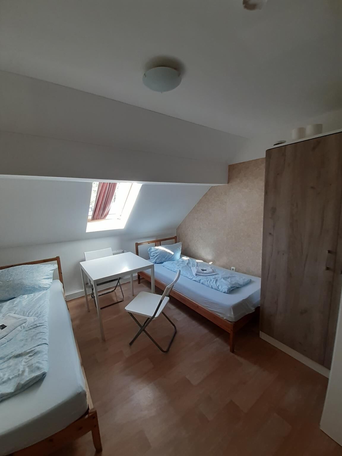 A small, compact room with a loft bed, a desk, and a single bed.