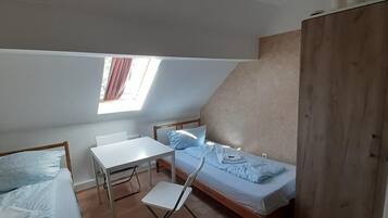 A small, compact room with a loft bed, a desk, and a single bed.