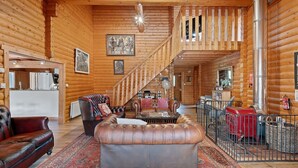 L’intérieur d’une cabane en rondins comprend un salon, un escalier et un coin cuisine.