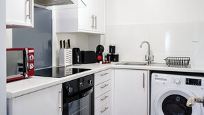 Una cocina compacta con microondas, cafetera y lavadora.