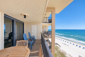 Un balcon avec vue sur la plage, des sièges d’extérieur et une table.