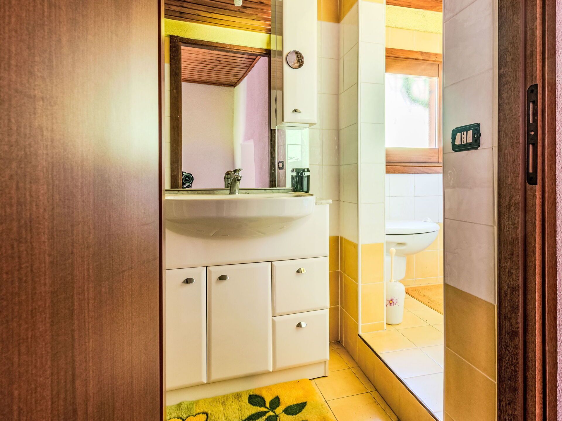 A bathroom with a white sink, mirror, and cabinets.