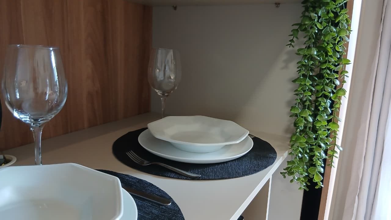 Ein Esstisch mit einem weißen Teller, einer Gabel und einem Weinglas.