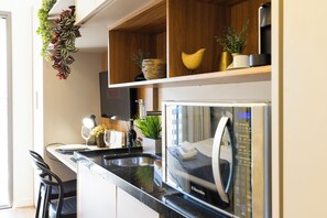 A modern kitchen with a built-in microwave, a coffee machine, and a wine glass on the counter. - Pool & AC Steps from Ibirapuera (Sao Paulo)