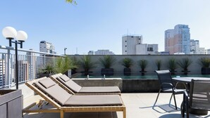 Une terrasse sur le toit avec des chaises longues, une piscine et une table avec des chaises.