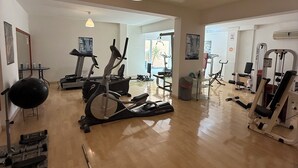 A spacious gym with various exercise equipment, including treadmills, stationary bikes, and weight machines.
