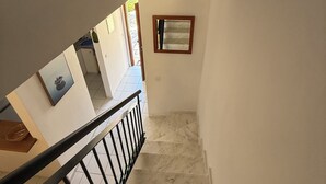 A staircase with a handrail, a framed mirror on the wall, and a door leading to another room.
