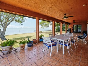 An outdoor patio with a table and chairs, potted plants, and a view of the water.