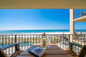 A balcony with a view of the beach, a bottle of wine, and a book. - Phoenix I 1024 1 Bedroom Condo (Orange Beach)