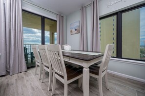 Comedor con una mesa y sillas, ventanas amplias y vistas panorámicas de la ciudad.