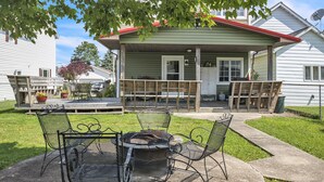 A patio with a fire pit and metal chairs, a covered porch with a red roof, and a house with a satellite dish. - Home Port - Spacious Retreat In Prime Location 4 Bedroom Home (Davis)