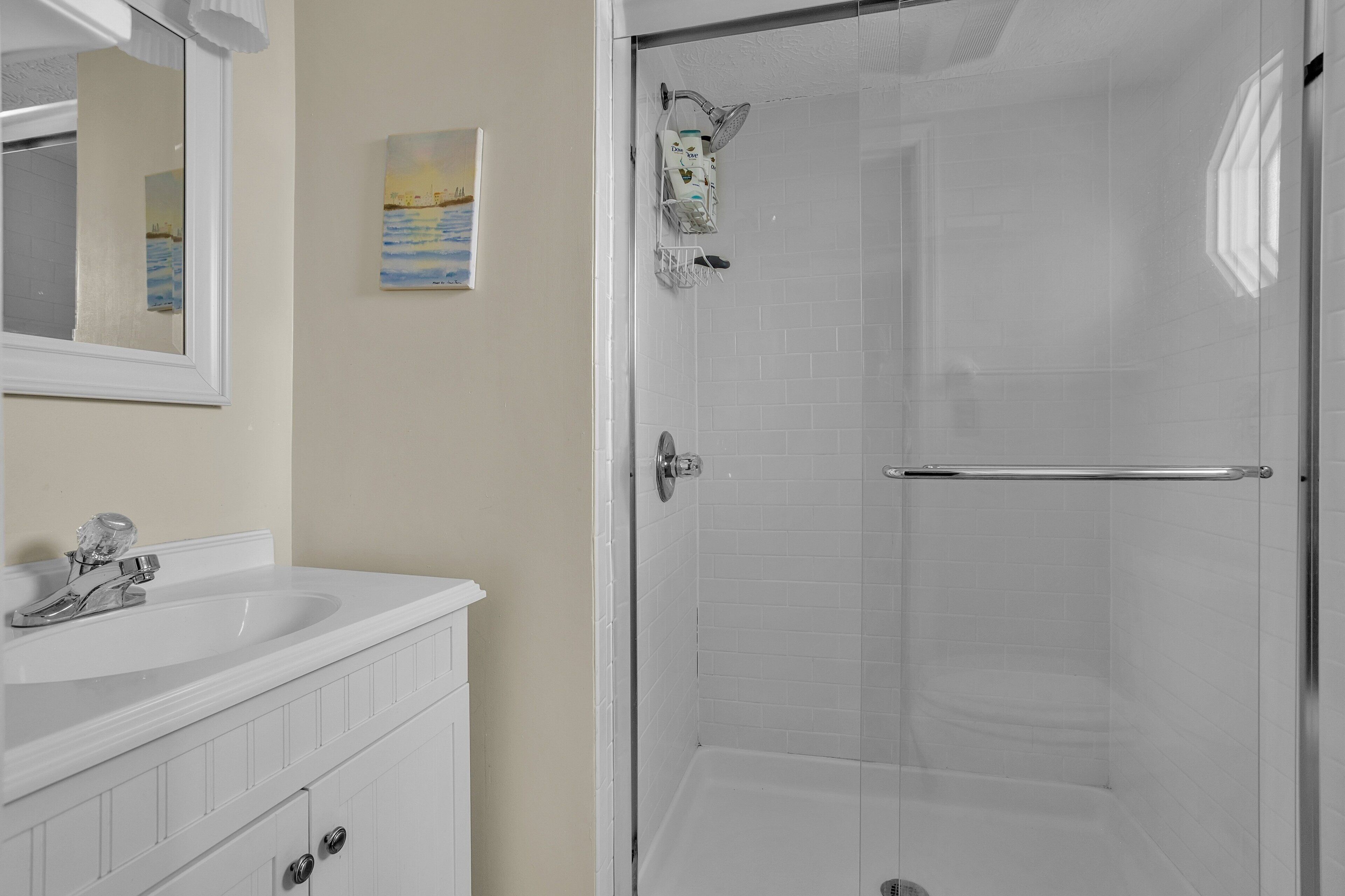 A bathroom with a white sink, mirror, and shower.