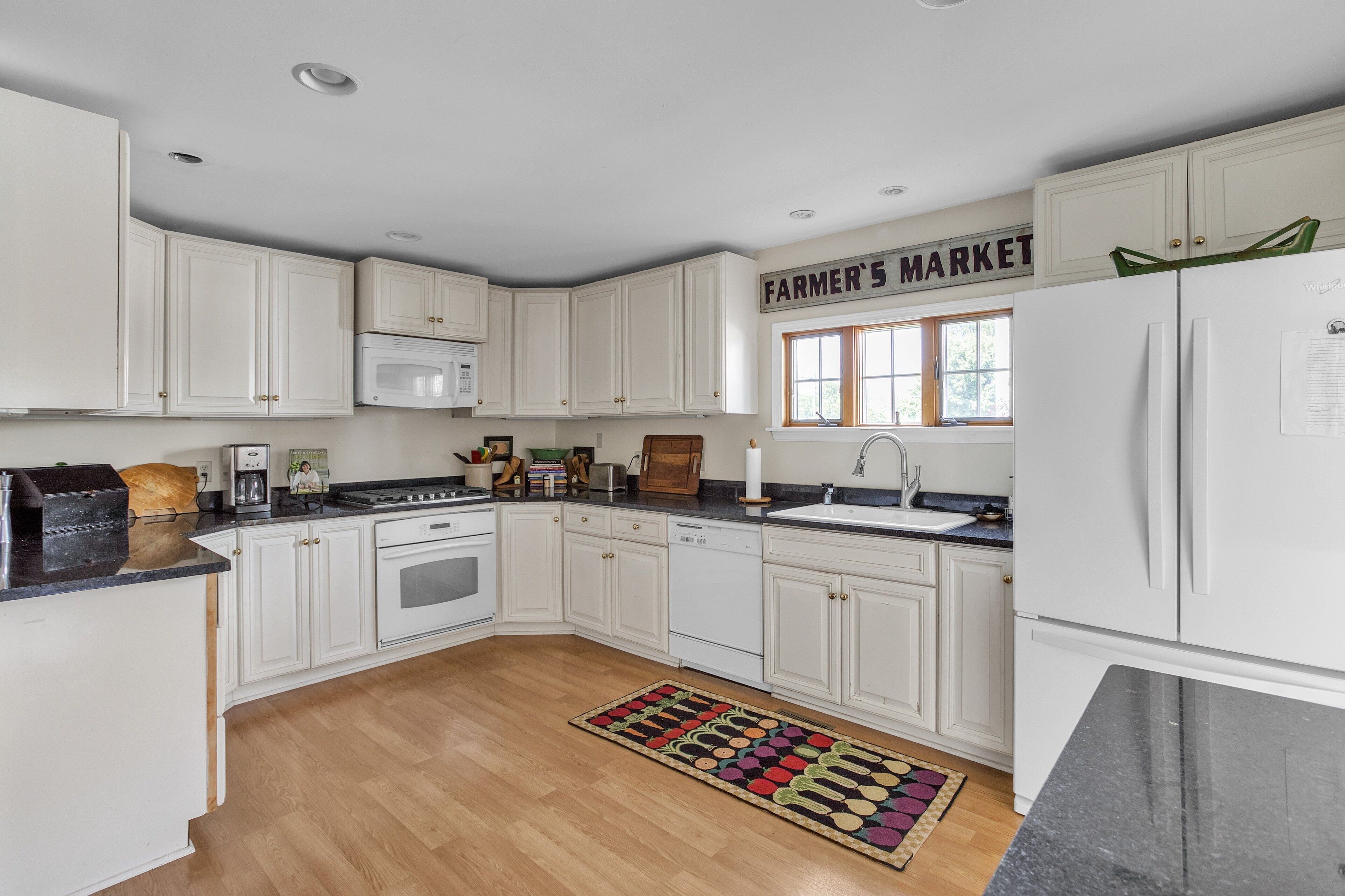 A kitchen with white cabinets, a microwave, a sink, and a refrigerator.