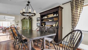 A dining area with a large wooden table, chairs, a chandelier, and a cabinet with decorative items. - Home Port - Spacious Retreat In Prime Location 4 Bedroom Home (Davis)