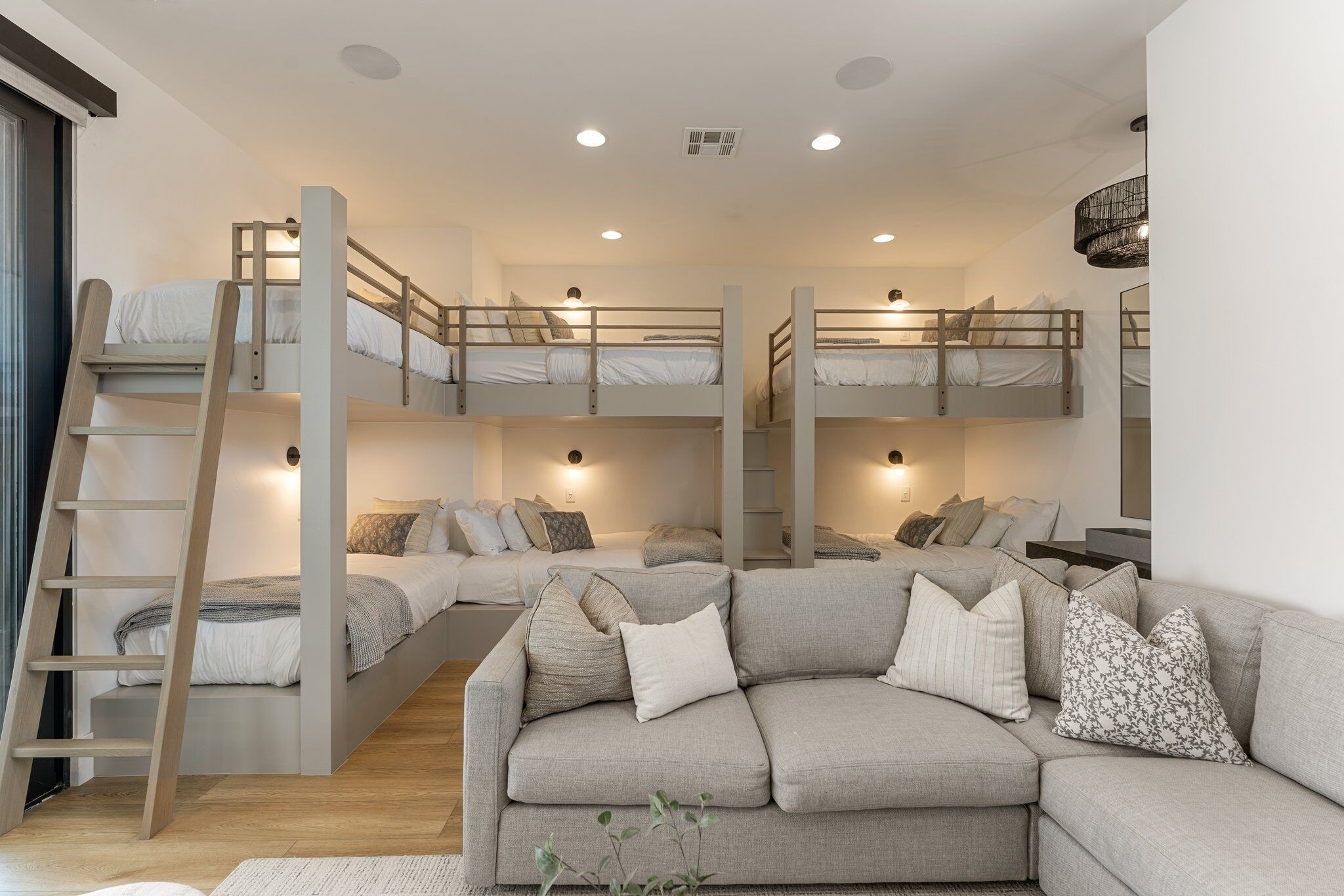 A multi-level bunk bed room with a sofa and ladder.