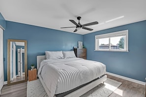A bedroom with a bed, a ceiling fan, a dresser, a window, and a mirror. - Modern Retreat With Private Pool & Yard 3 Bedroom Home (Tinley Park)