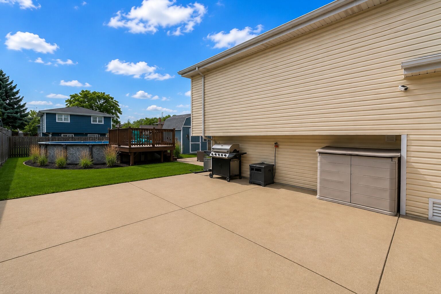 Een garage met woonhuis, een oprit van beton, een barbecue en een vuilnisbak.