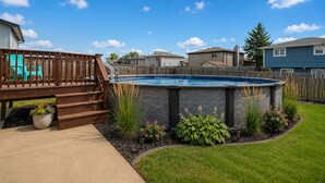 Un jardin avec une piscine, une terrasse en bois et un jacuzzi en pierre.