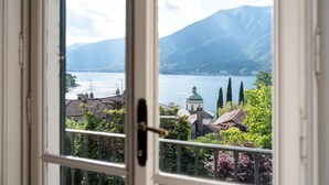 Blick aus einem Fenster auf einen See, Berge und Gebäude.