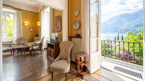 Ein geräumiges Wohnzimmer mit gemusterten Möbeln, Seeblick und einem Balkon mit Geländer.