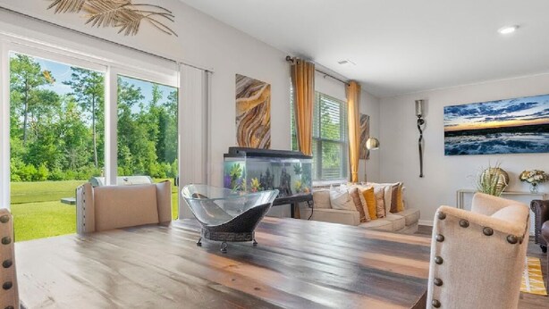 Una sala de estar moderna con una mesa de madera grande, asientos cómodos, un acuario y vistas al exterior.