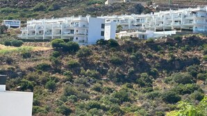 A hillside residential area with modern white buildings, some with balconies, and a rocky hill in the background. - Holiday Home 'Great Townhouse Close To The Beach' with Sea View, Wi-Fi and Air Conditioning (Manilva)