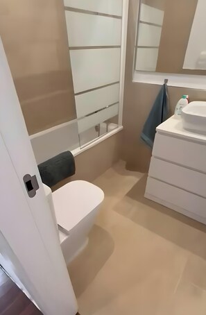 Une salle de bain équipée de toilettes, d’un lavabo, d’un miroir et d’une serviette accrochée au mur.