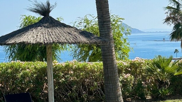 A beachside lounge area with two lounge chairs and a thatched umbrella, overlooking the ocean. - Holiday Home 'Great Townhouse Close To The Beach' with Sea View, Wi-Fi and Air Conditioning (Manilva)