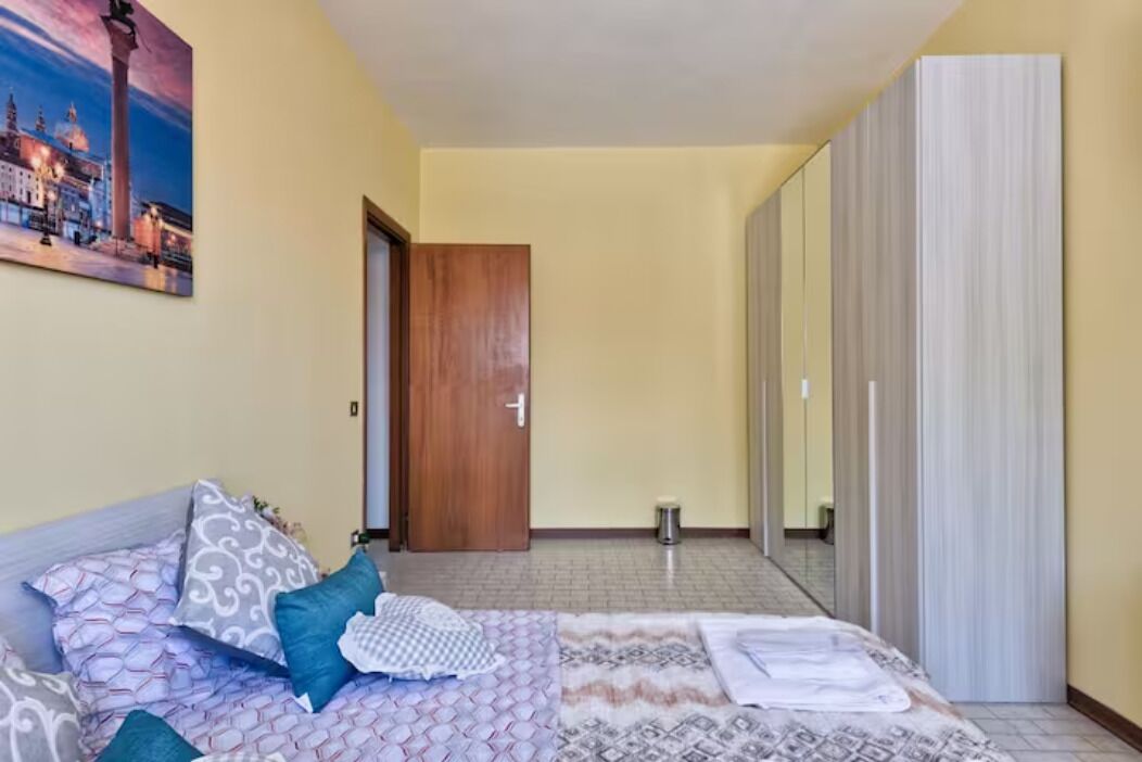Ein Hotelzimmer mit einem Bett, einer Holztür, einem Spiegel und einem Bild an der Wand.