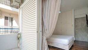 A bedroom with a bed, a wardrobe, and a balcony with a hose. - Barbara's sweet home Glyfada by ΜΡS (Glifada)