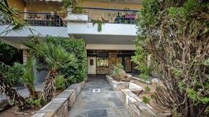 A courtyard with stone pathways, potted plants, and a balcony with railings. - Barbara's sweet home Glyfada by ΜΡS (Glifada)