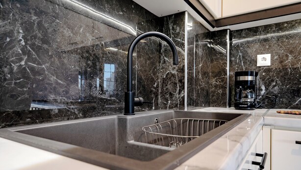 A modern kitchen with a sleek black faucet, a built-in sink, and a coffee maker on the countertop. - Barbara's sweet home Glyfada by ΜΡS (Glifada)
