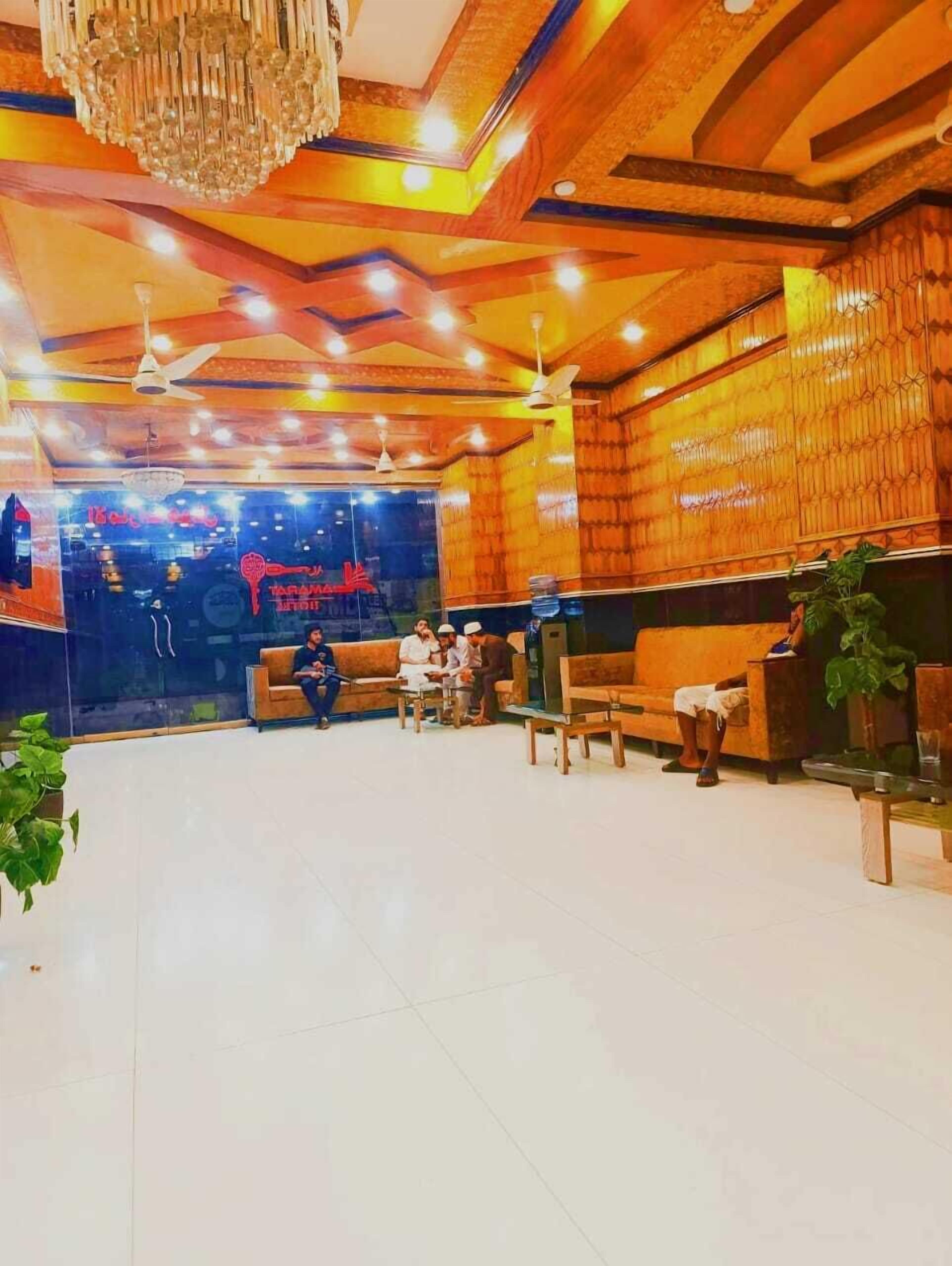 Eine geräumige Lobby mit hoher Decke, Holzvertäfelung und einem Chandelier. Es gibt mehrere Sitzbereiche mit Sofas und Sesseln.