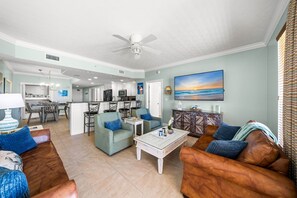A spacious living area with a dining table, sofas, a coffee table, and a kitchen in the background.