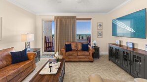 A living room with a brown leather sofa, a coffee table, a TV, and a ceiling fan.