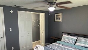 A bedroom with a bed, a ceiling fan, a nightstand, and a door leading to a closet. - Palmetto Ellenton | Nature + Smart Comfort (Palmetto)