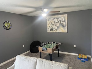 A room with grey walls, a foosball table, a dartboard, and a horse-themed painting. - Palmetto Ellenton | Nature + Smart Comfort (Palmetto)