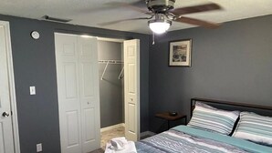 A bedroom with a bed, a ceiling fan, a door, and a small table. - Nature & Comfort: Charming 3BR Palmetto-Ellenton Home, Sleeps 6, WiFi & AC (Palmetto)