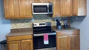 A kitchen with wooden cabinets, a microwave, an oven, and a blender on the countertop. - Nature & Comfort: Charming 3BR Palmetto-Ellenton Home, Sleeps 6, WiFi & AC (Palmetto)