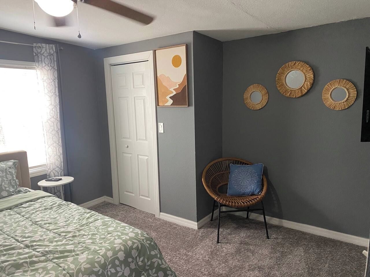 Une chambre à coucher comprenant un lit, une chaise, une petite table, une porte et des éléments de décoration murale.