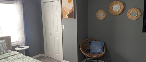 Une chambre à coucher comprenant un lit, une chaise, une petite table, une porte et des éléments de décoration murale.
