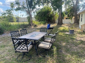 An outdoor dining area with a table and chairs, surrounded by grass and trees. - Palmetto Ellenton | Nature + Smart Comfort (Palmetto)